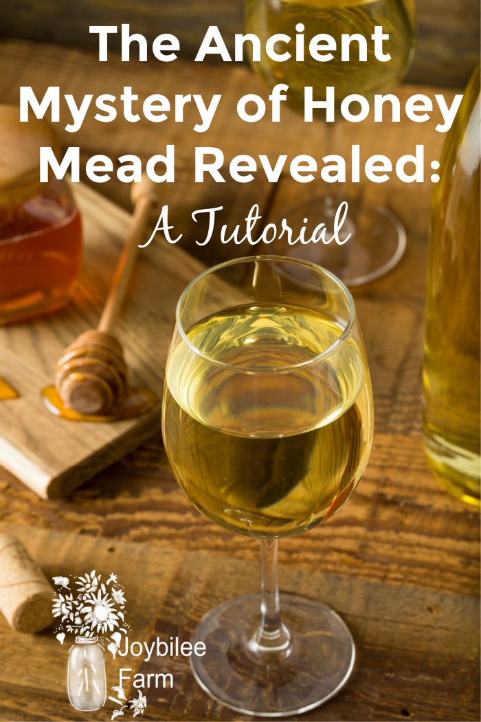 white mead in a glass with honey in the background on a wooden table.