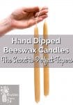 A hand holding two beeswax taper candles