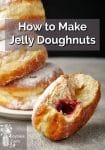 A stack of jelly doughnuts on a plate in front of a half eaten jam filled doughnut