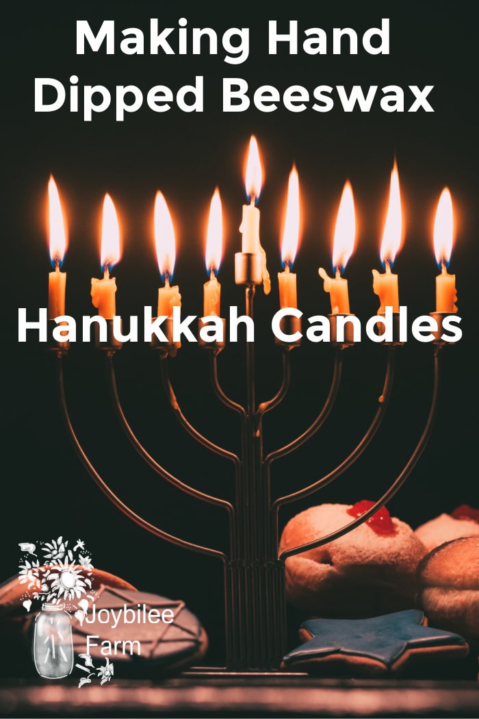 lit hanukkah menorah on a dark background, with donuts and cookies at the base