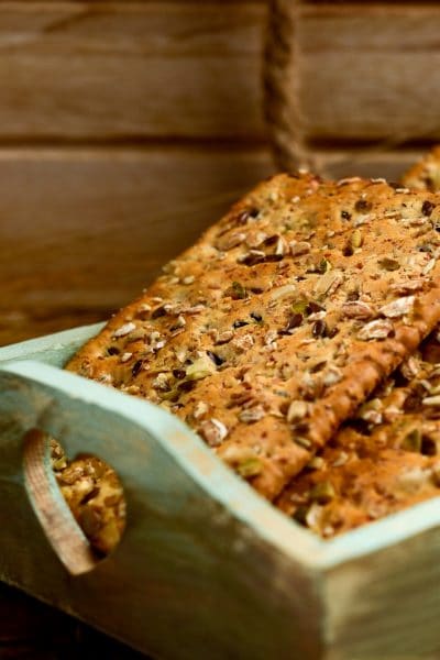 A wooden tray holding homemade seed crackers