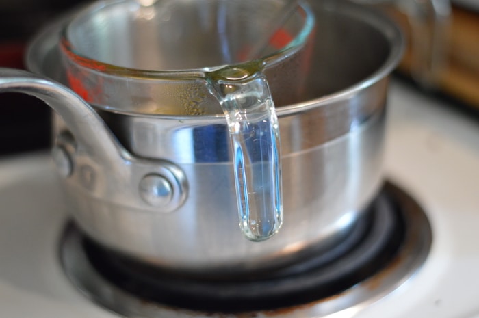 metal pan and glass measuring cup on a stovetop burner