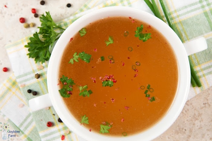 a bowl of bone broth with parsley and green onion floating on it