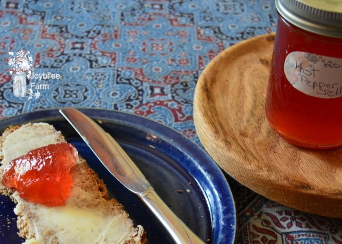 hot pepper jelly on a piece of bread with a plate and butter knife