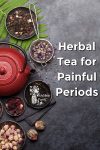A teapot and dried herbs on a slate background