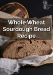 A sliced loaf of sourdough bread in front of a basket of bread