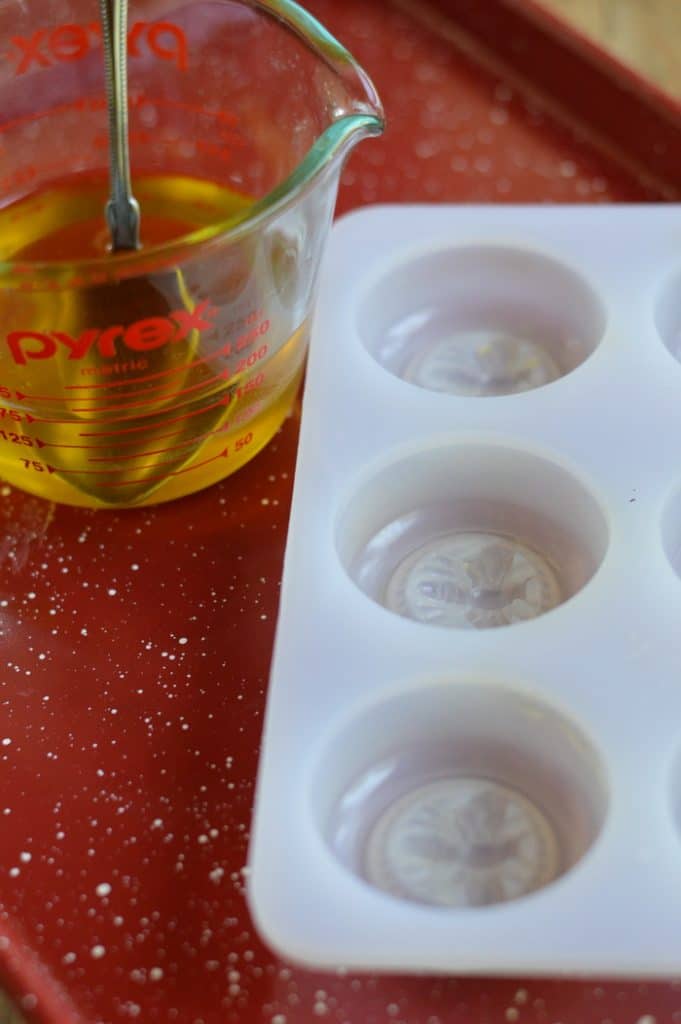 Melted beeswax in a glass measuring cup beside a decorative mold for making bars 