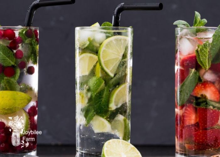 glasses of fresh herbs and seltzer with herb simple syrup