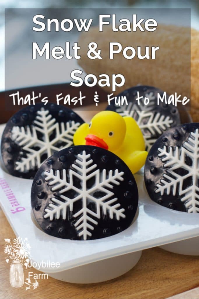 soap that has a white snowflake design on a dark blue bar, with a yellow rubber duck in the middle.